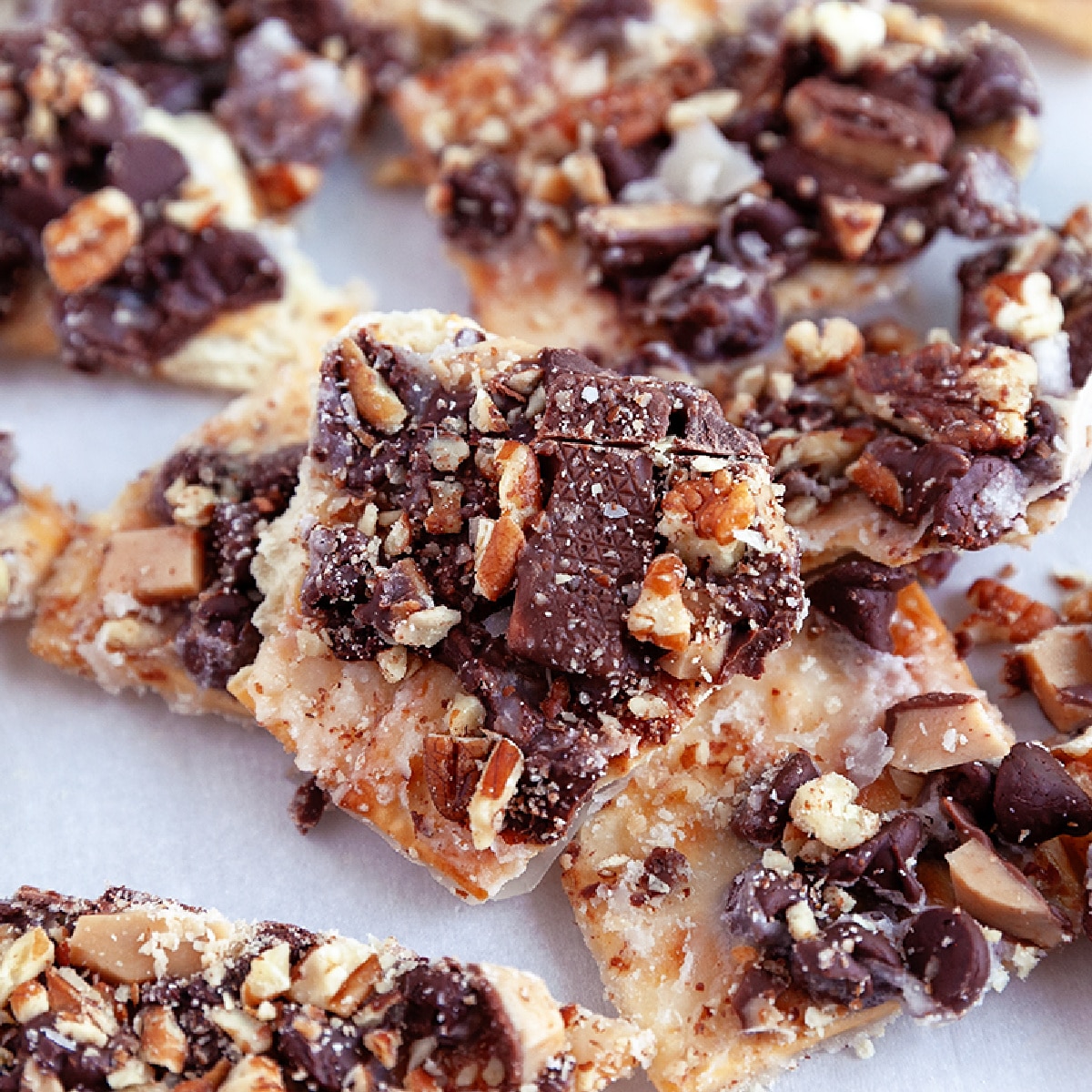 Square photo showing broken up bits of Saltine Toffee. 