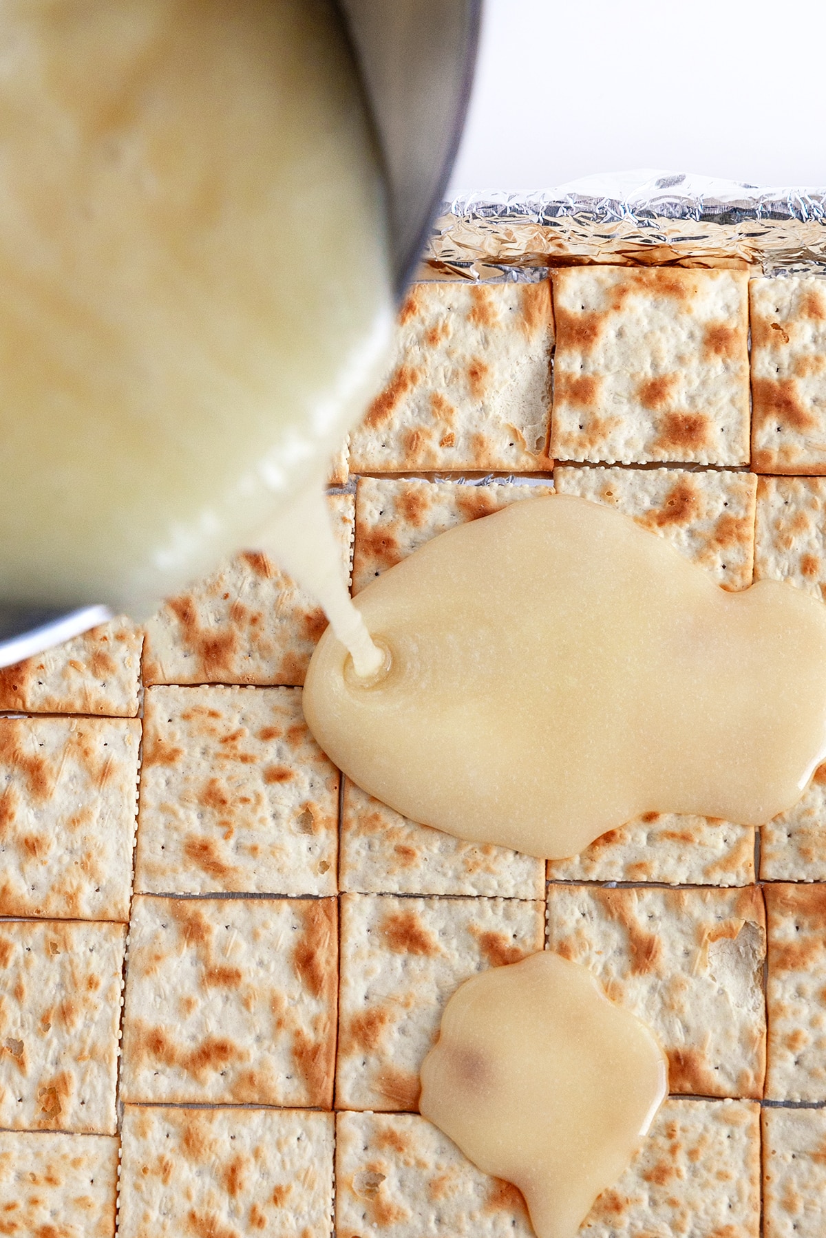 Pouring toffee over the saltine crackers. 