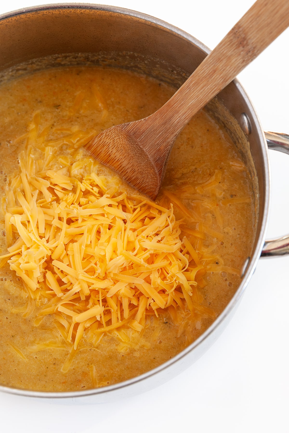 Overhead shot of added cheese to a pot of soup. 
