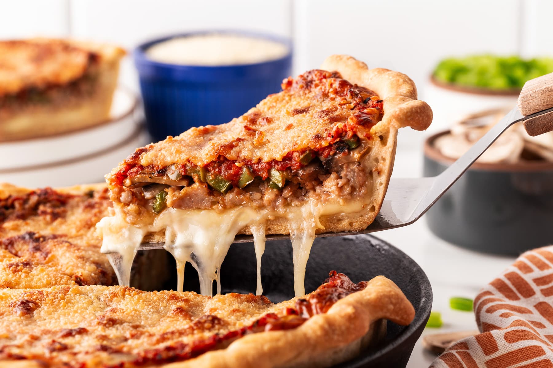 Horizontal of a slice of deep dish pizza showing a cheese pull. 