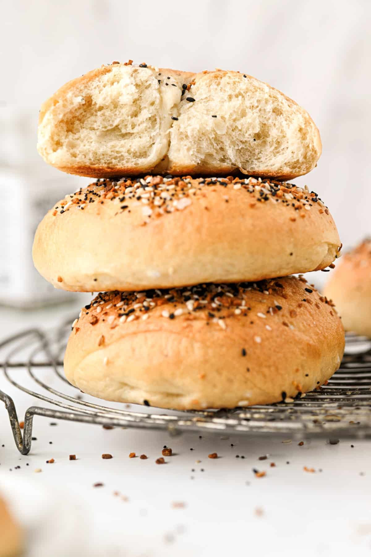 Stacked bagels with the one on top broken in half to see the inside. 