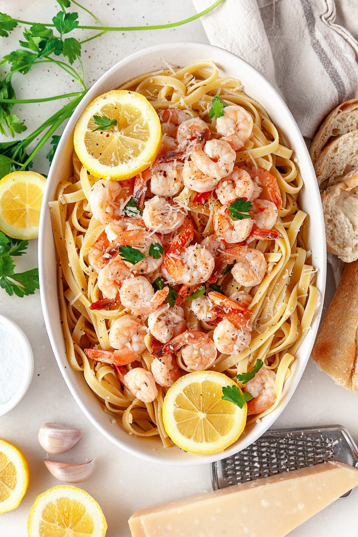 Overhead shot of Garlic Butter Shrimp Pasta Recipe in an oval baking dish with slices of lemon. 