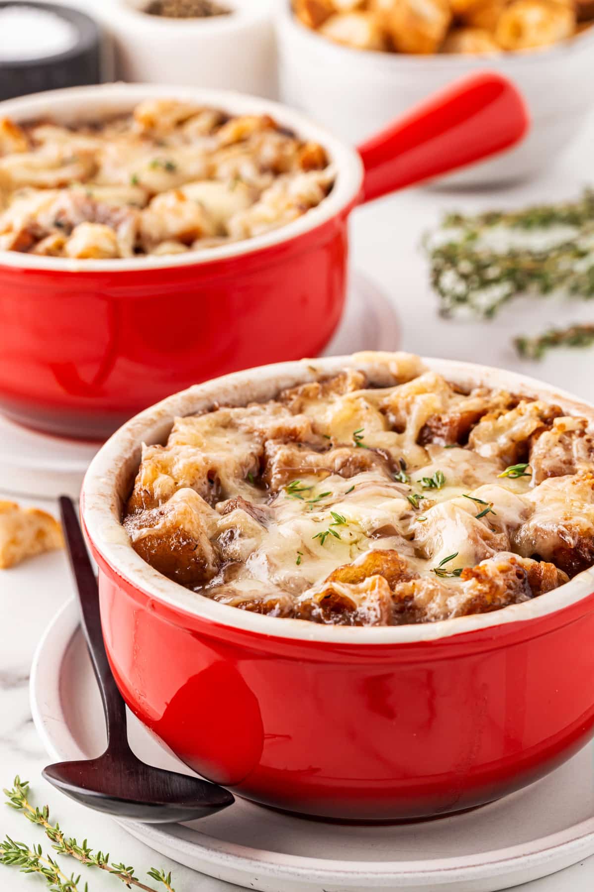 Front view of French Onion Soup for Two in red bowls with handles. 