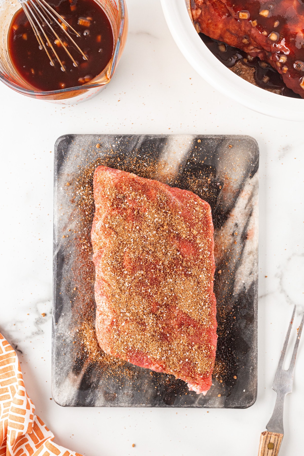 Overhead shot of ribs on a marble slab covered in seasoning. 