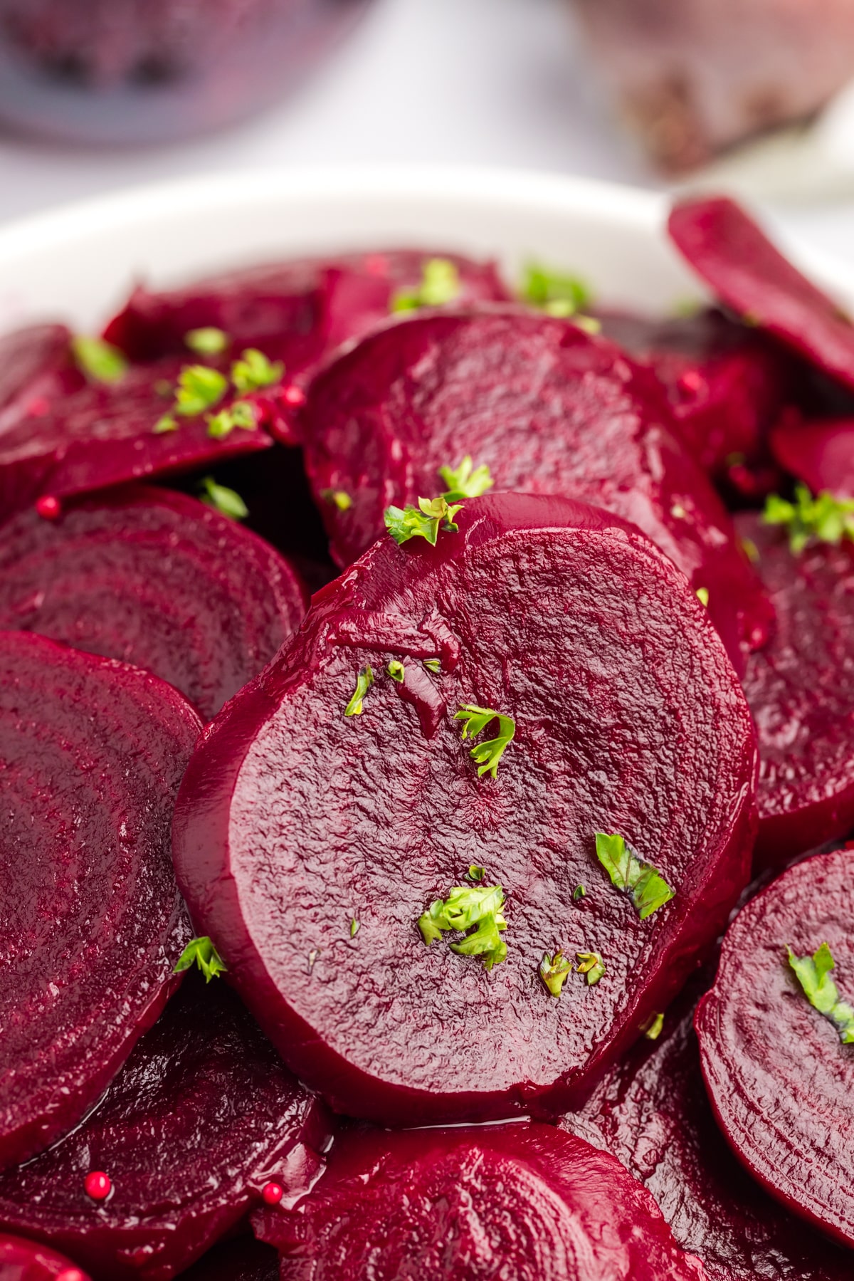 Close-up of sliced pickled beets with parsley on top. 