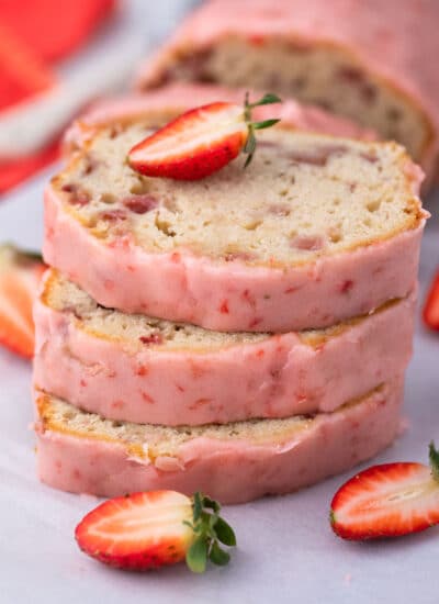 Sliced Strawberry Pound Cake stacked with half a strawberry on top.