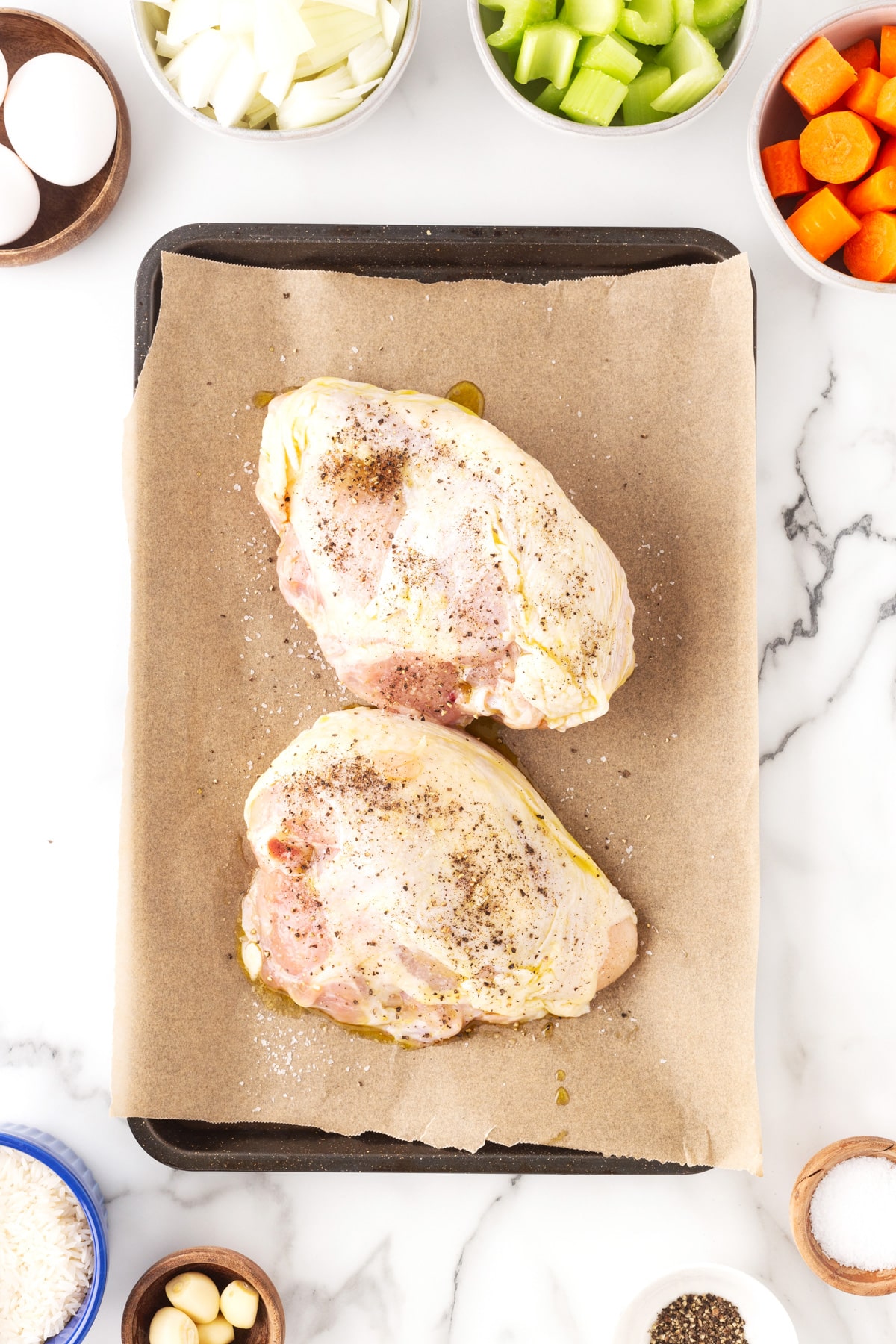 Chicken breasts, skin-on, bone-in on parchment lined baking sheet and ready for the oven. 