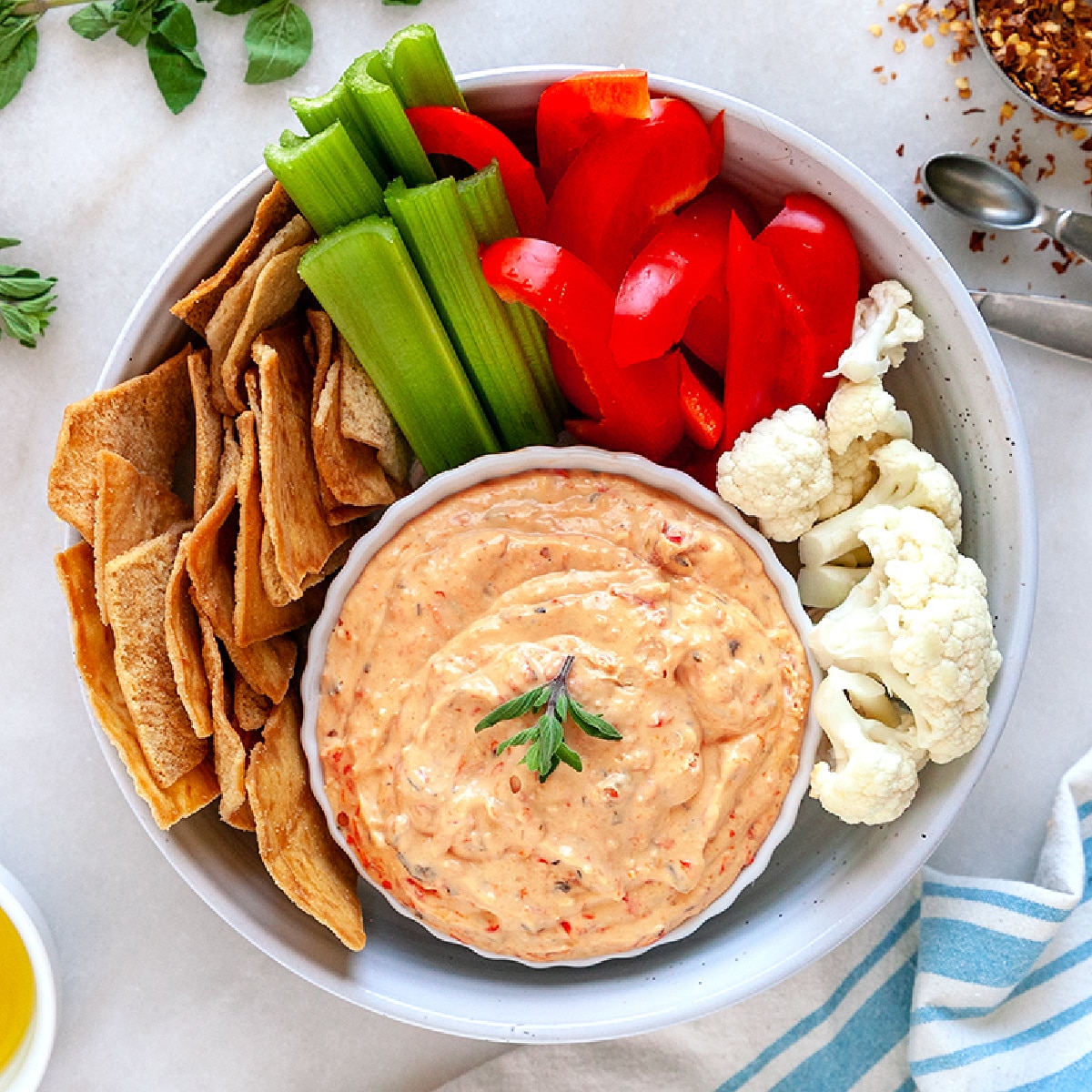 Square picture of dip with crudites and pita chips. 