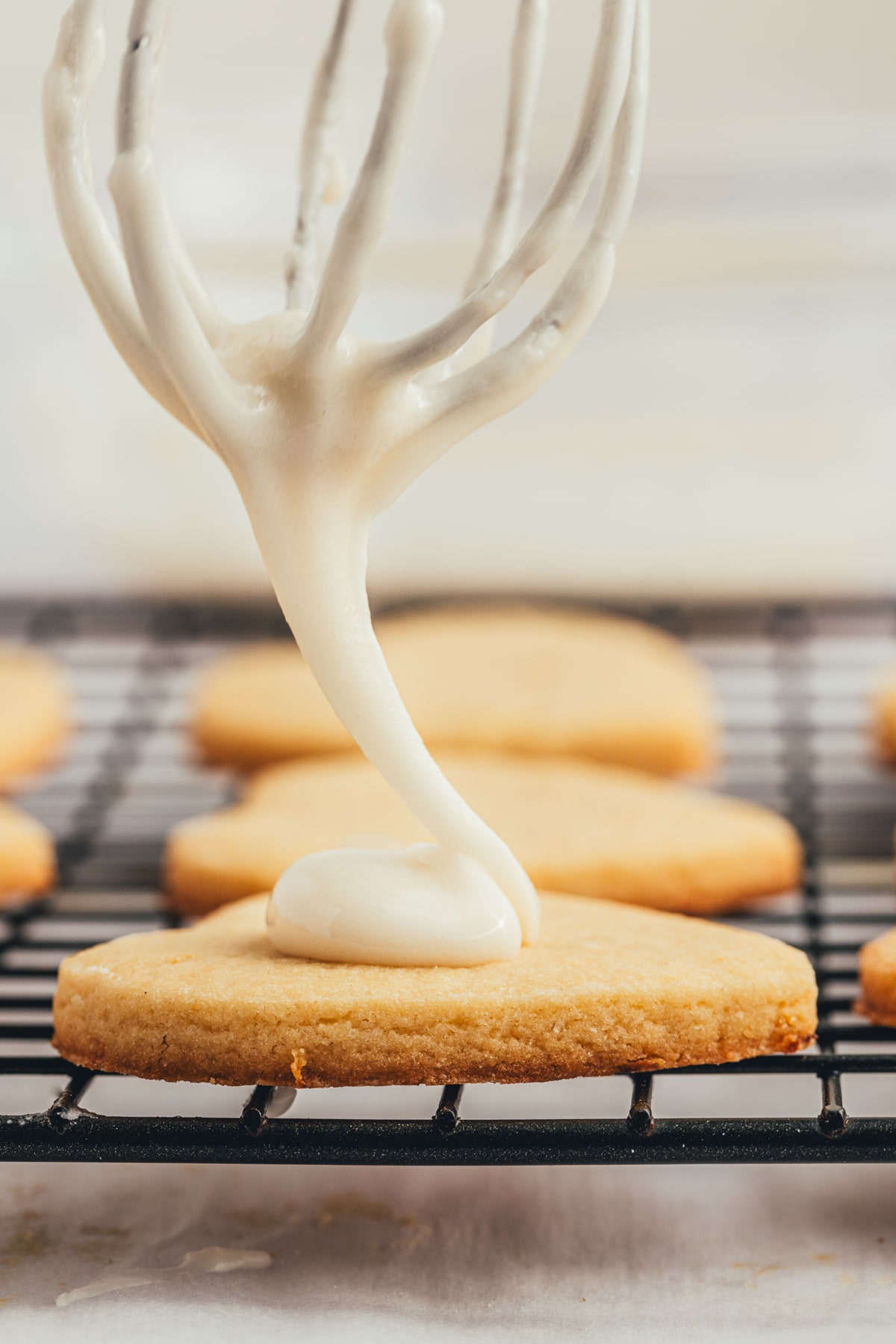 Icing going onto a cookie from a whisk. 