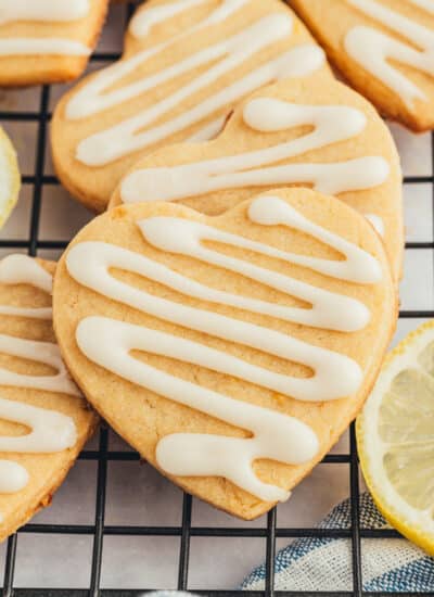 Lemon Shortbread Cookies overlapping on a cooling rack with lemon slices.