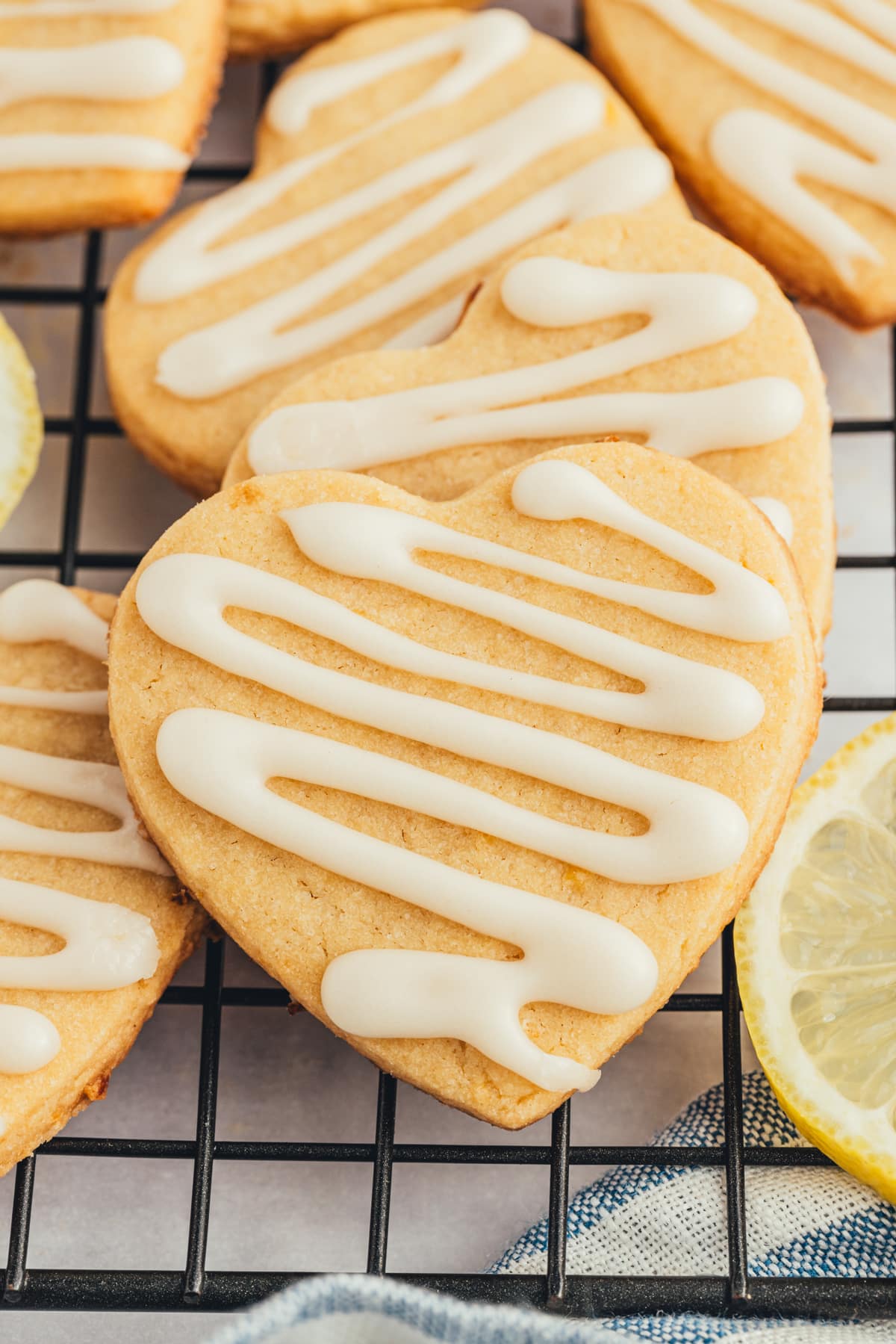 Cookies on a cooling rack stacked on each other with a slice of lemon on the side. 