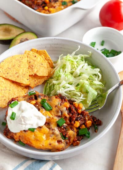 Plated Mexican Casserole with chips, shredded lettuce and topped with sour cream.