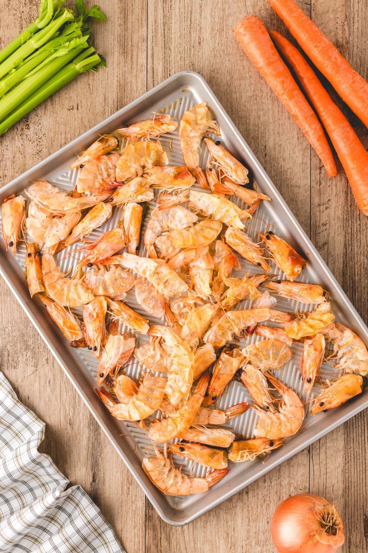 Cooked shrimp shells and heads on a baking sheet.
