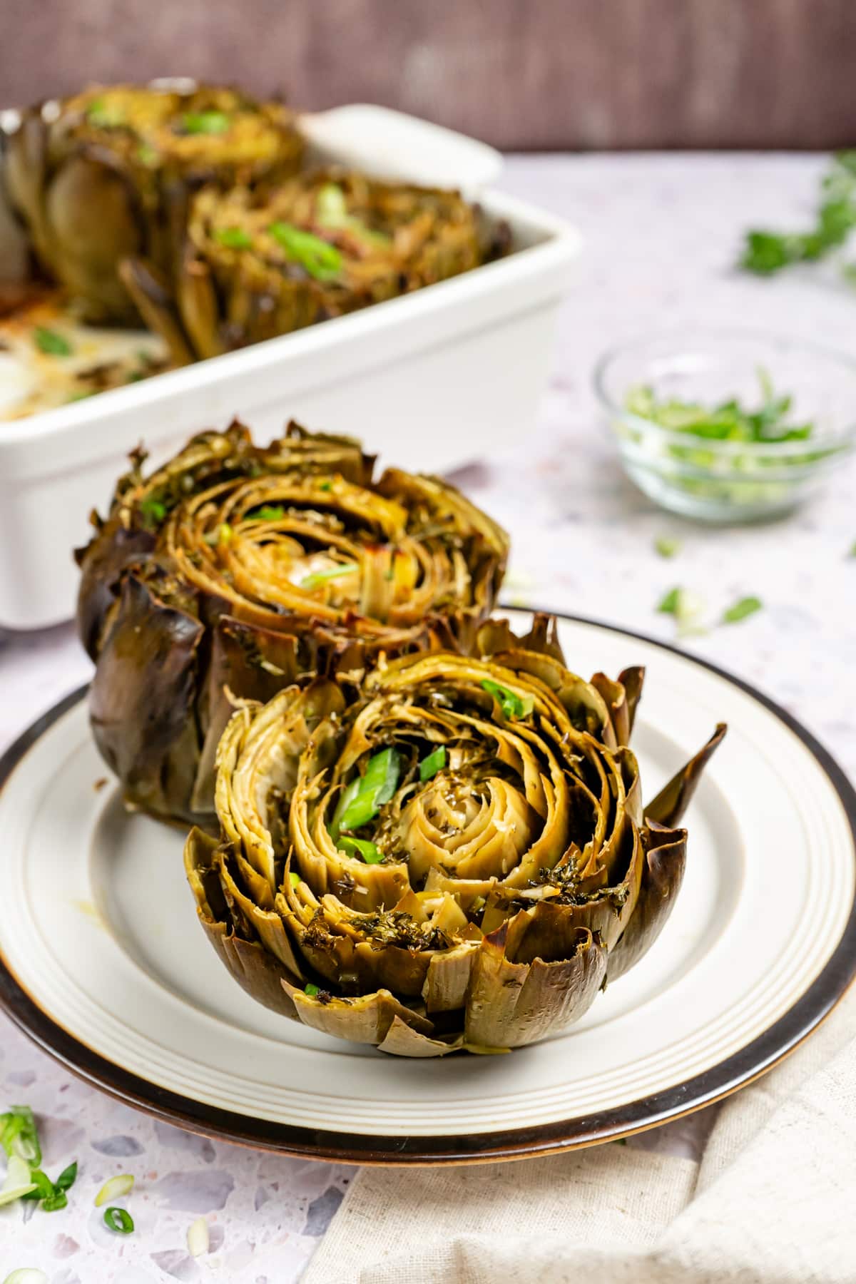 Two cooked artichokes on a plate. 