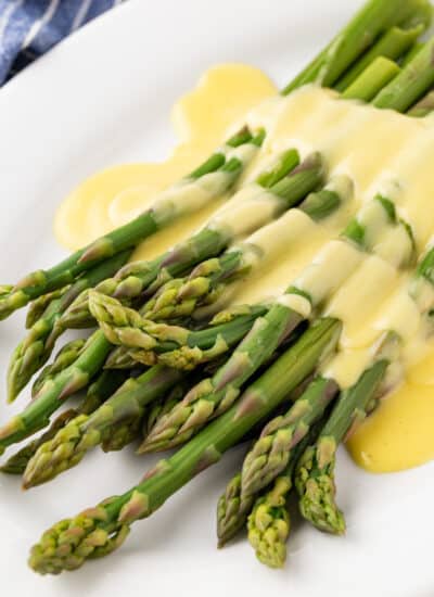 Asparagus with Hollandaise Sauce on a white plate.