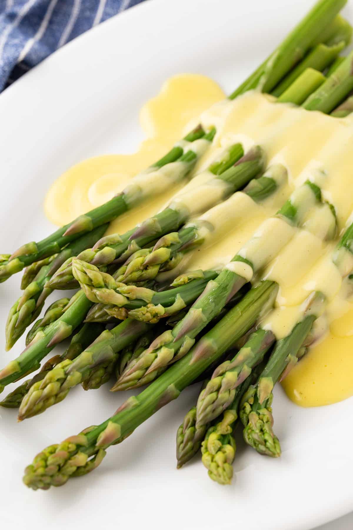 A white plate with Asparagus with Hollandaise Sauce. 