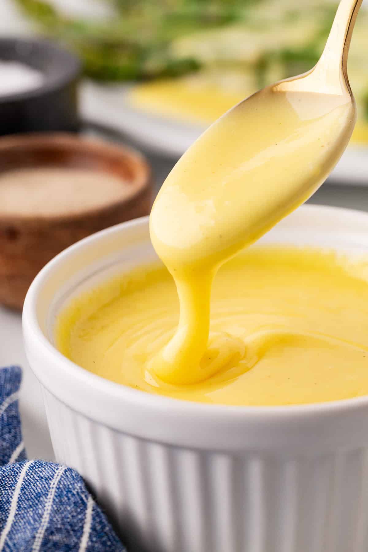 A spoonful of sauce pouring back into a ramekin. 