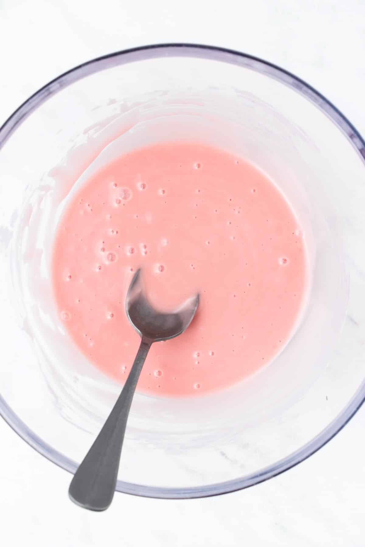 Pink glaze in a bowl with a spoon. 