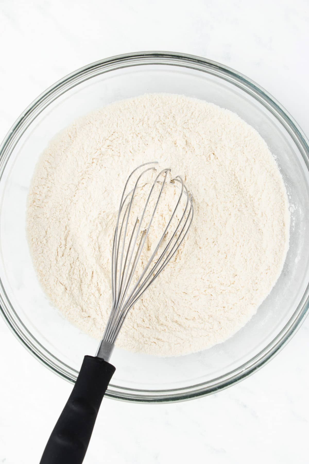 Dry ingredients in a bowl with a whisk. 