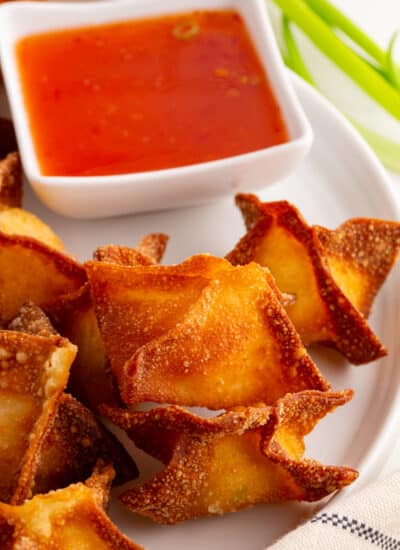 Close-up of Crab Rangoon on a plate with dipping sauce.