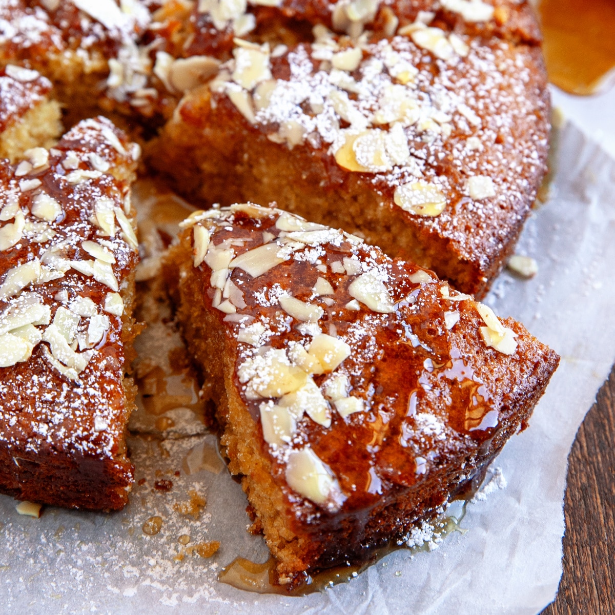 Square image of honey cake sliced and dripping in honey. 