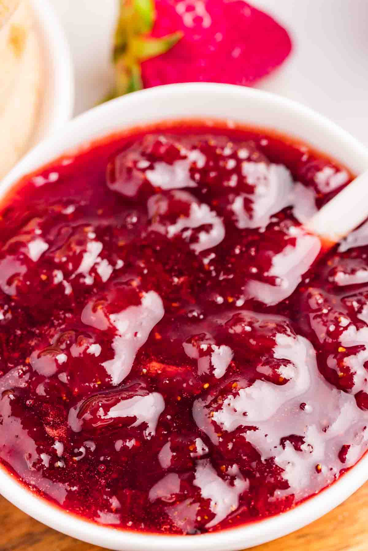 Jam in a white bowl with a white spoon. 