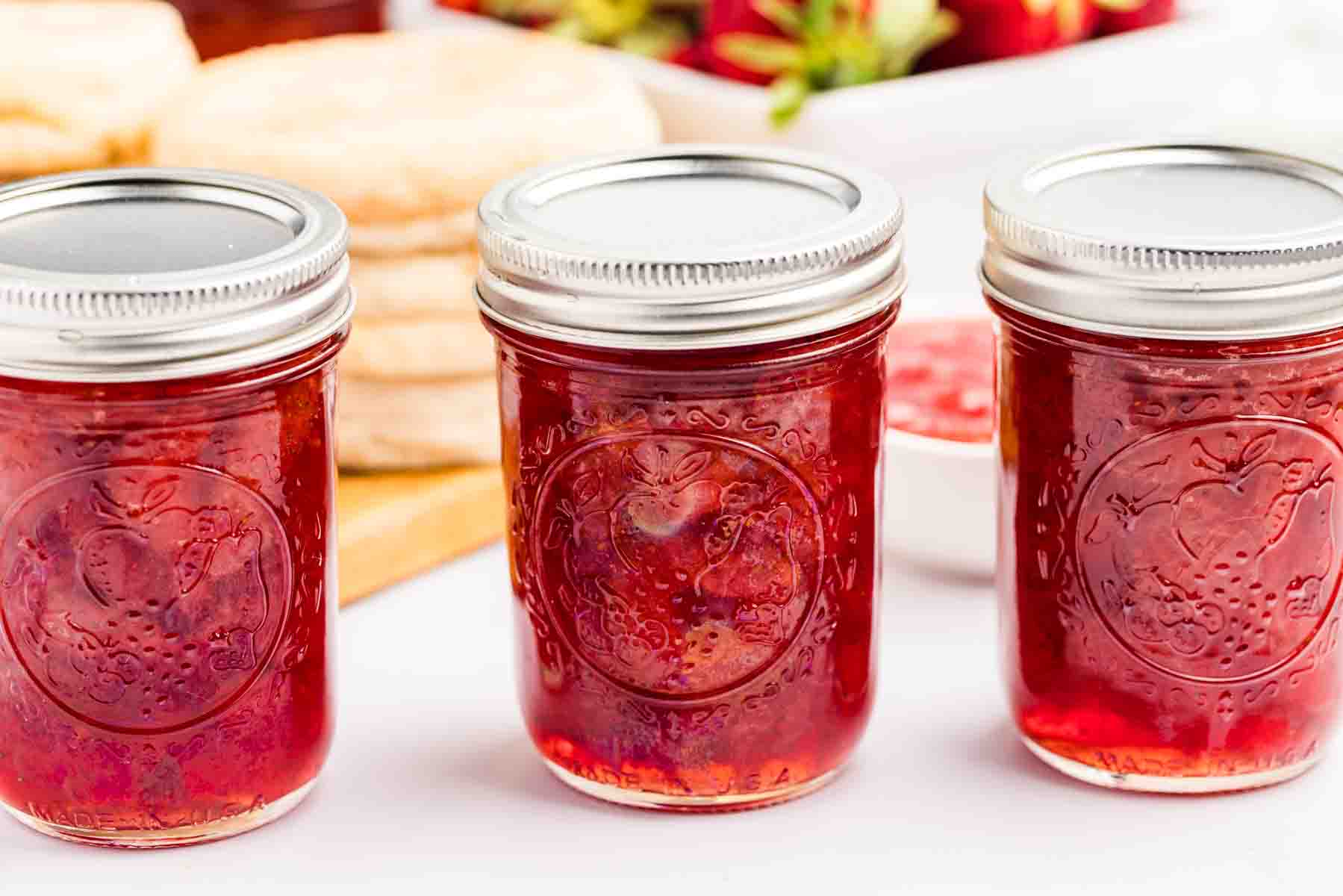 Three jars in a row of strawberry jam. 
