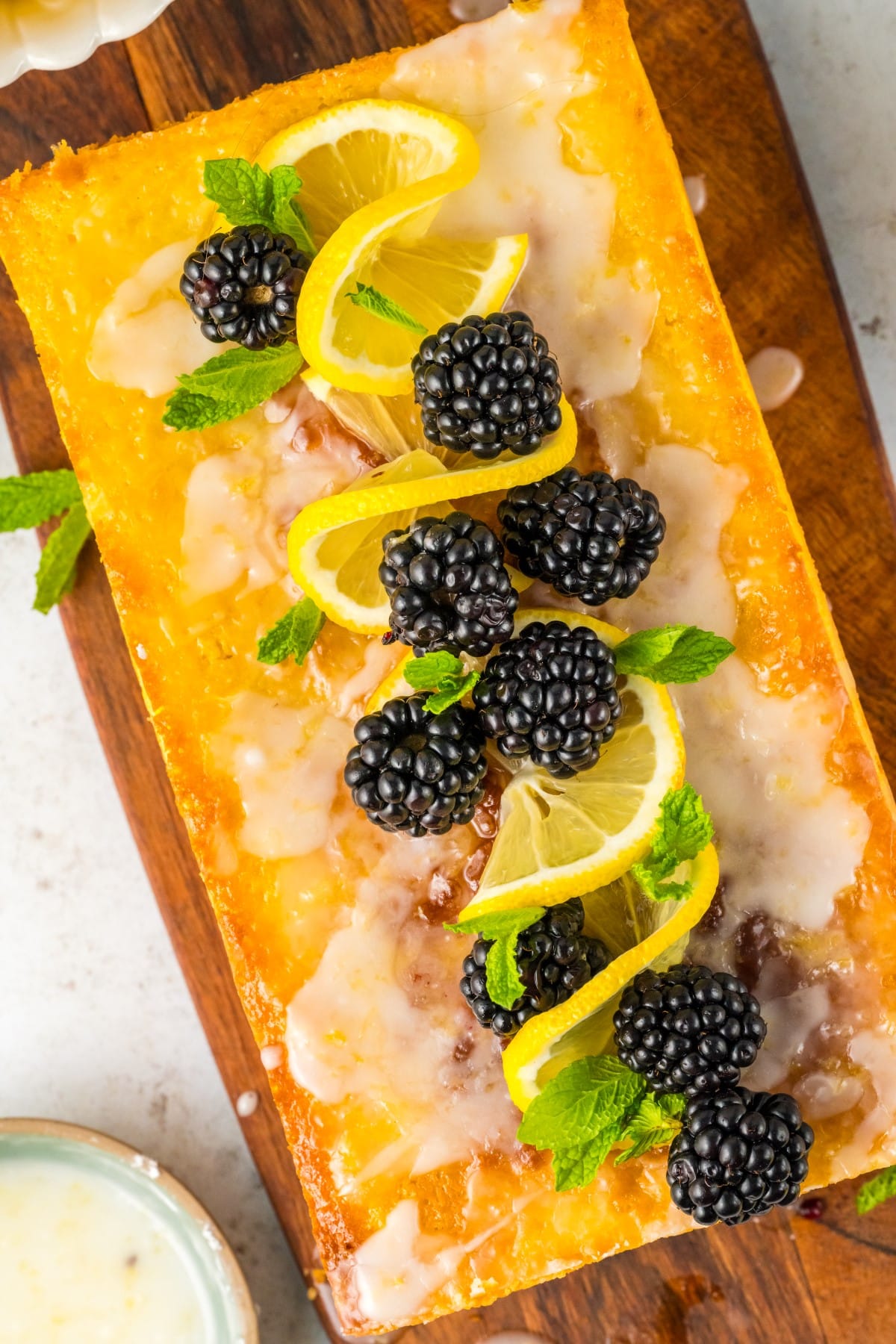 Overhead shot of Lemon Blackberry Cake decorated with lemon twists, mint and blackberries. 