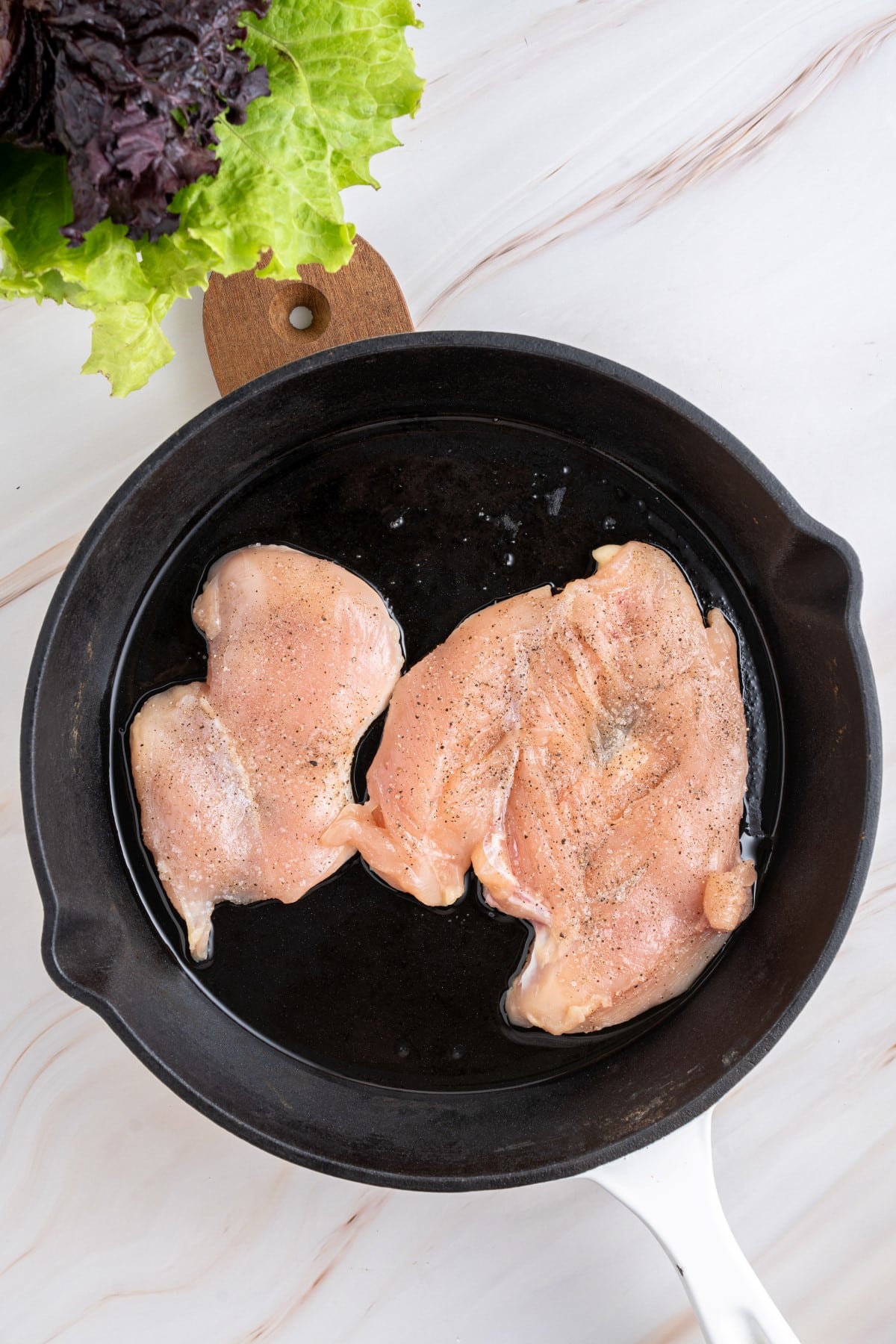 Chicken added to a cast iron pan. 