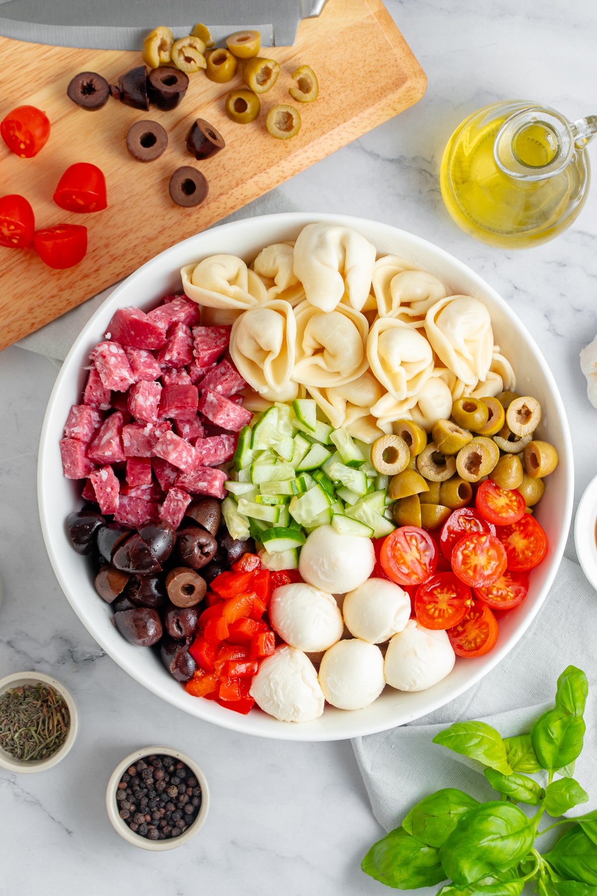 Tortellini salad being mixed into a large bowl.