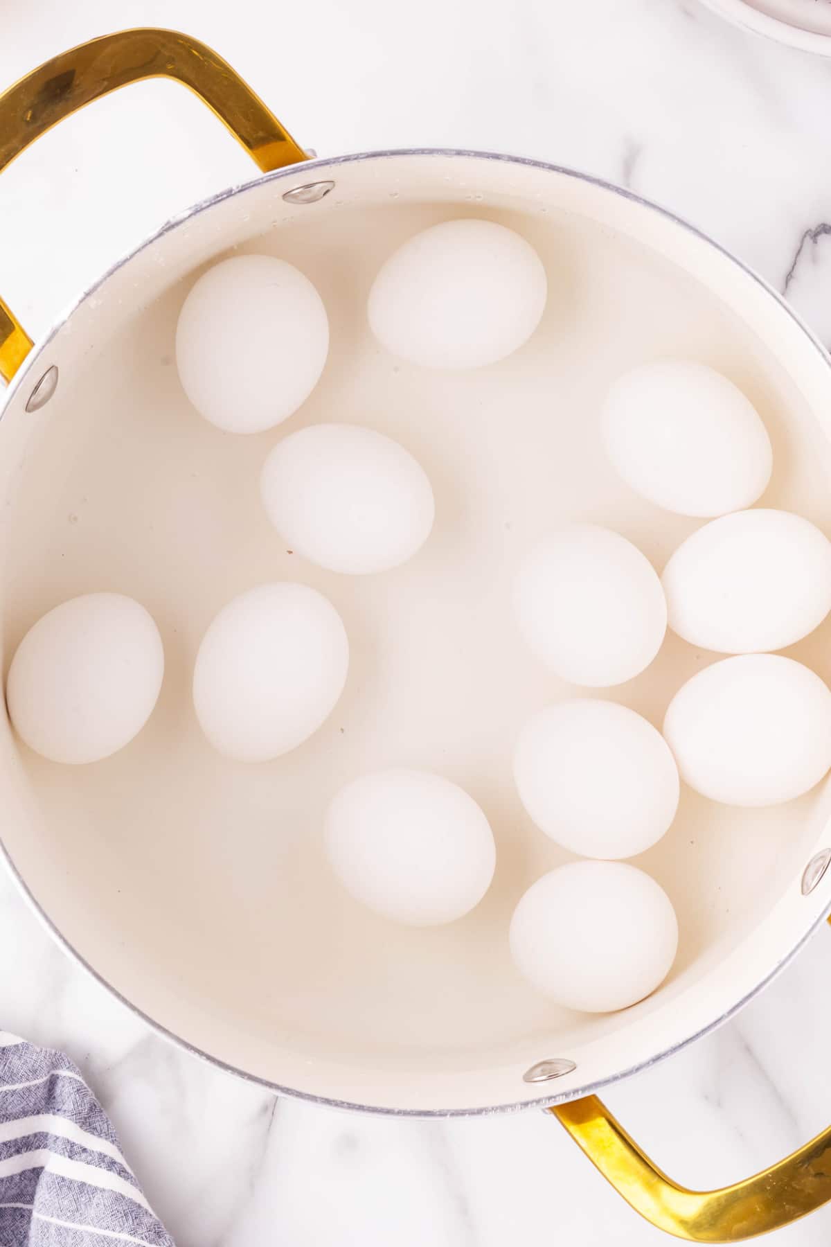 Overhead shot of eggs in water in a pot. 