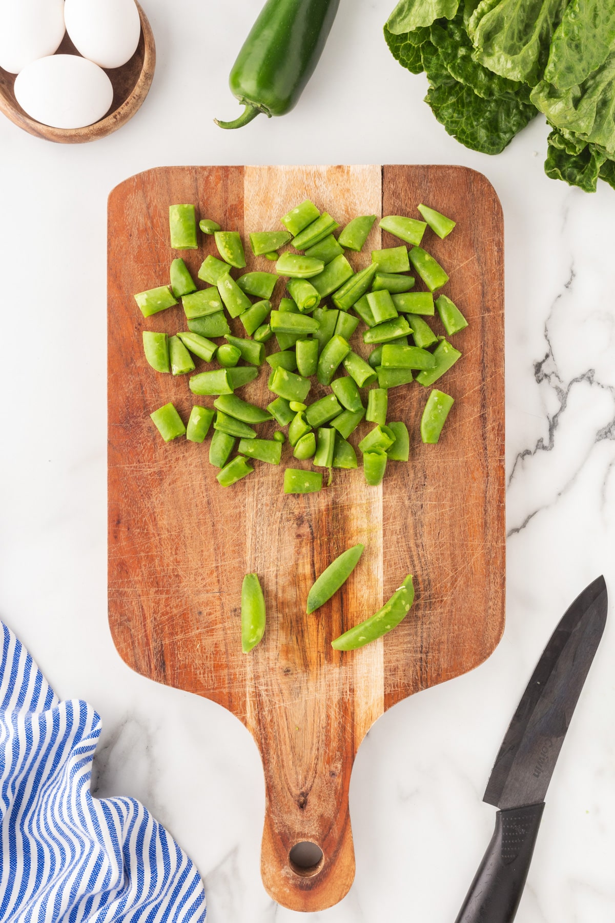 Snap peas chopped on a cutting board. 