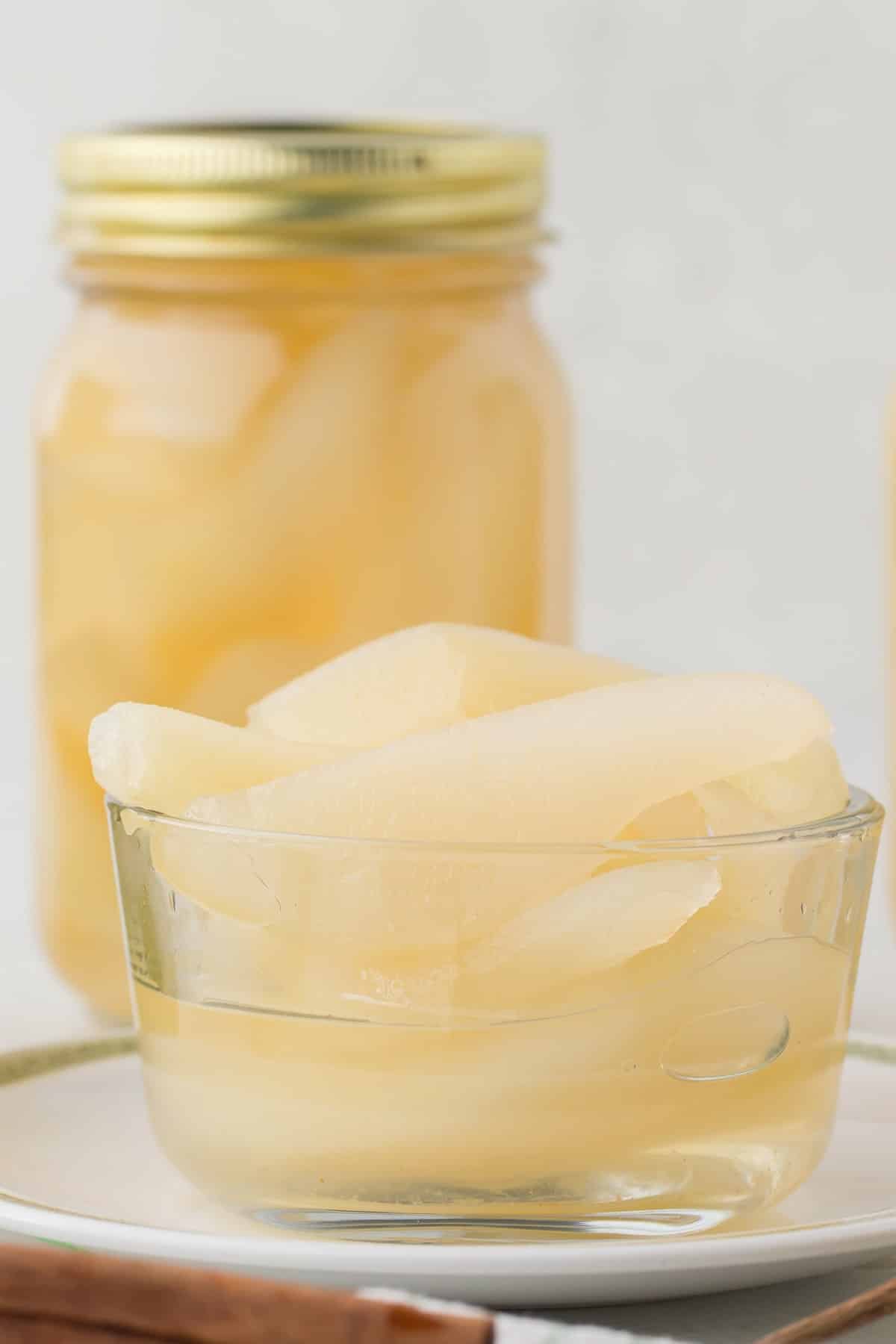 Close-up of a bowl of pears with a jar in the background.