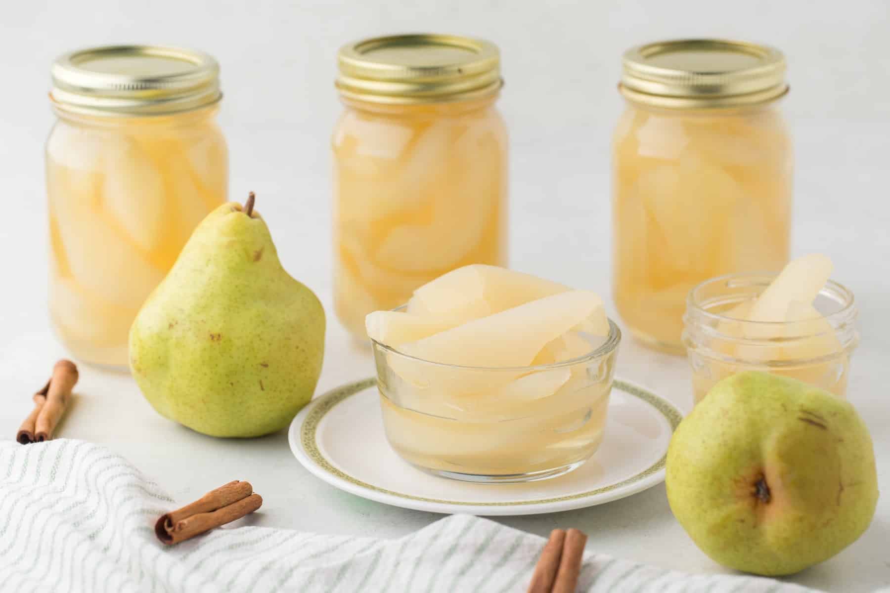 Horizontal picture of canned pears plus pears in a bowl, small jar and fresh.. 