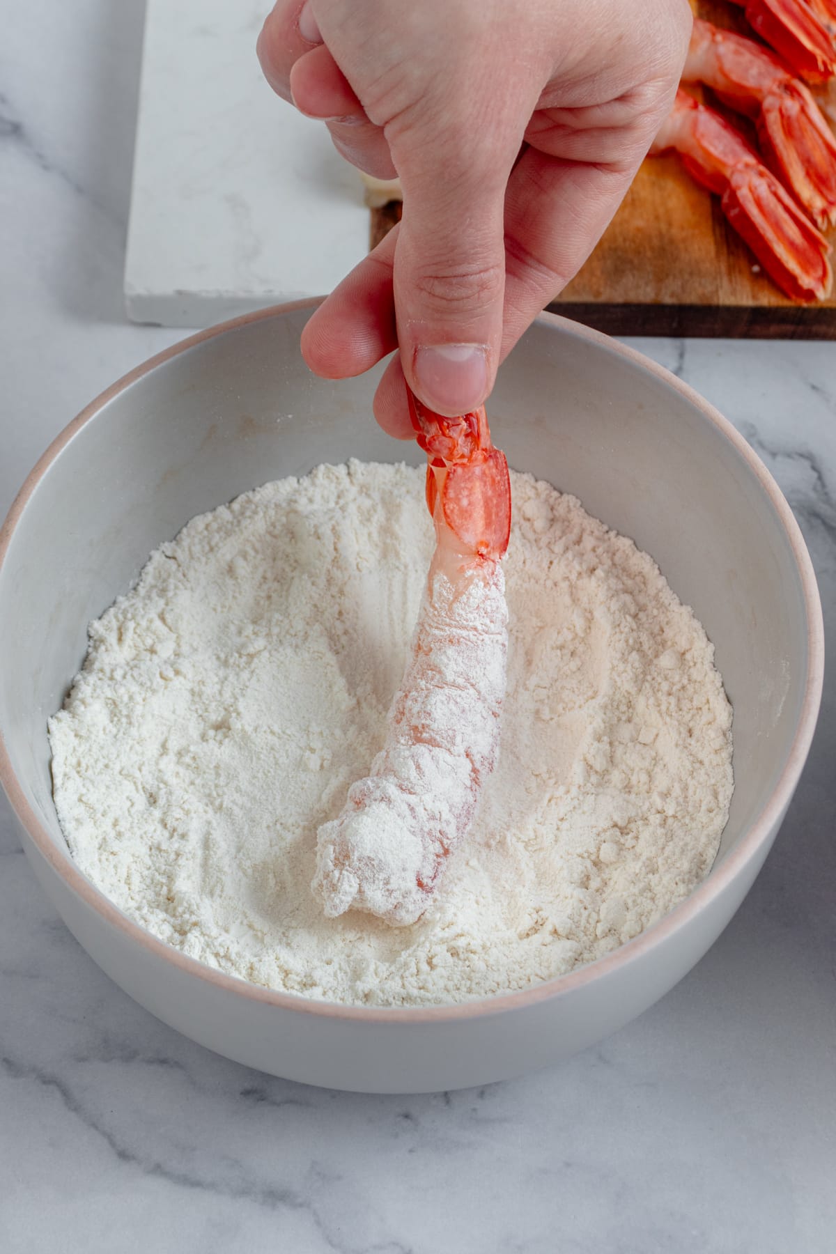 Shrimp being coated in all-purpose flour.