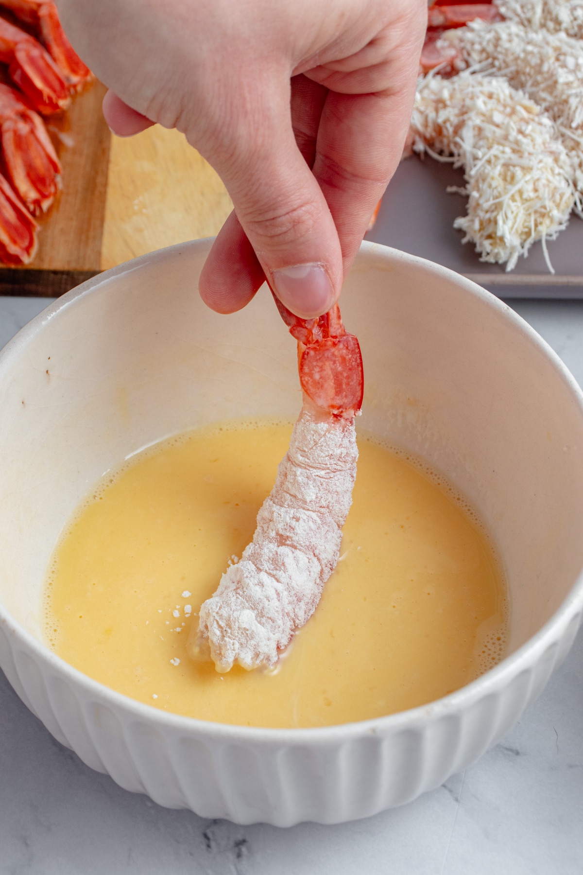 Shrimp being coated in an egg mixture.