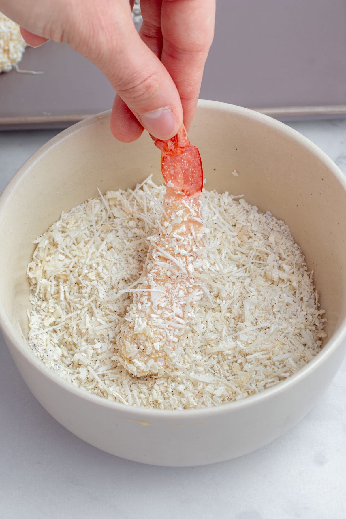 Shrimp being coated with shredded coconut.