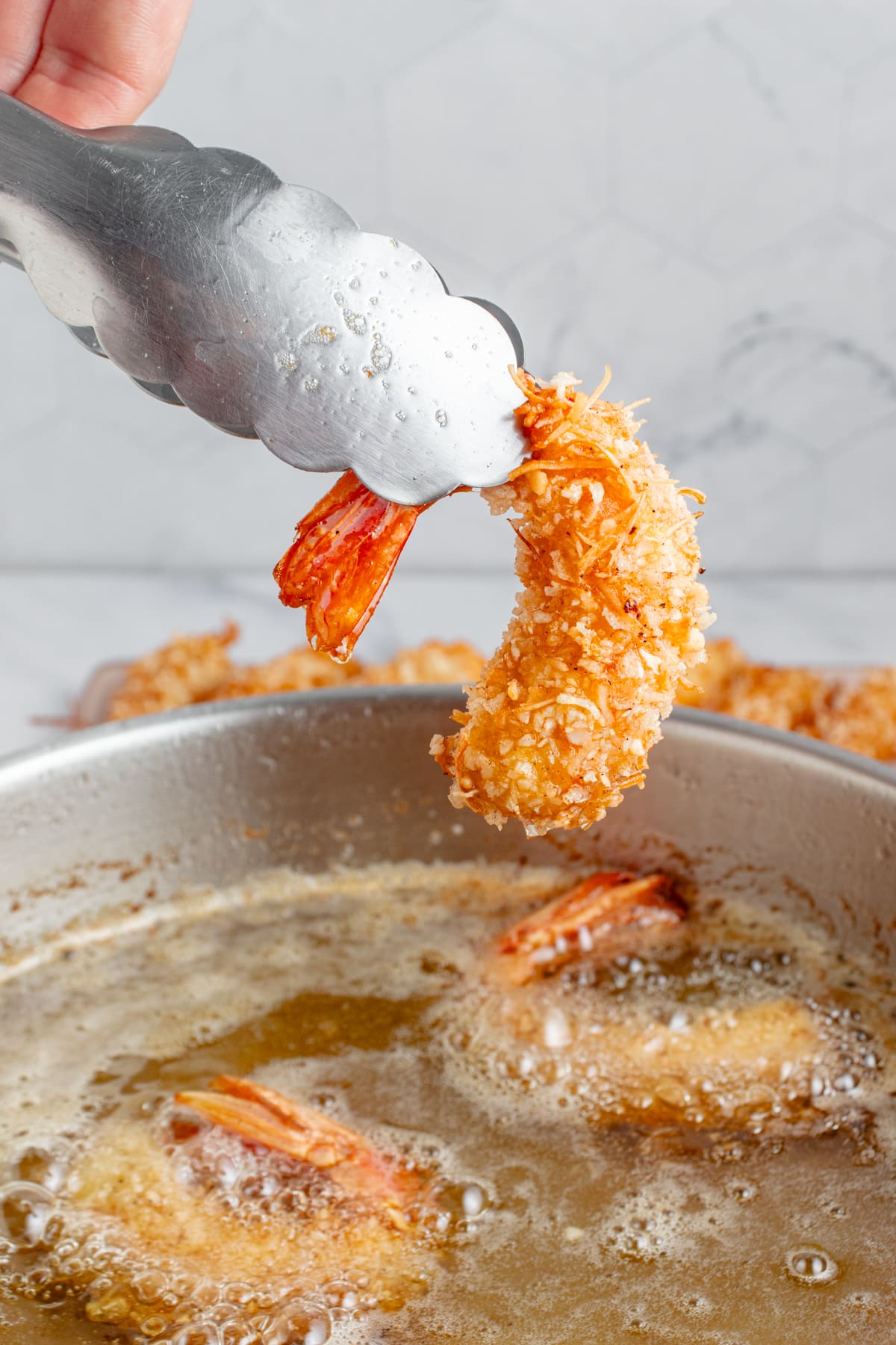 Just fried coconut shrimp being taken out of the oil.