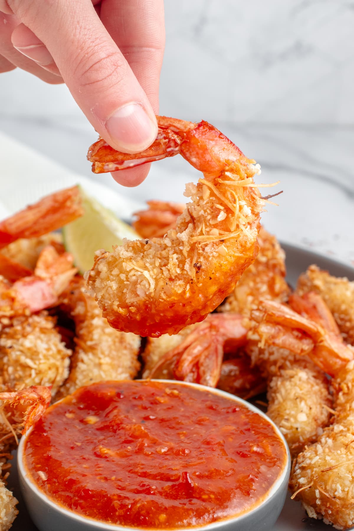 Coconut Shrimp Recipe being dipped in sauce. 