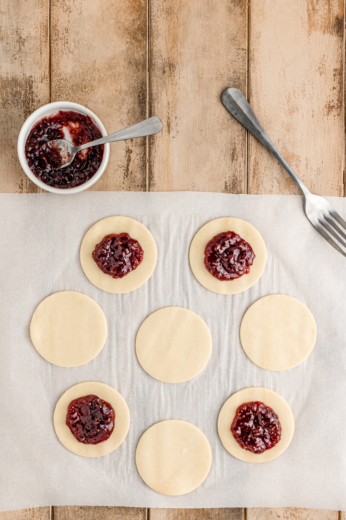 Adding jam to the circles of dough. 