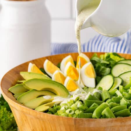 Pouring salad dressing on the salad.