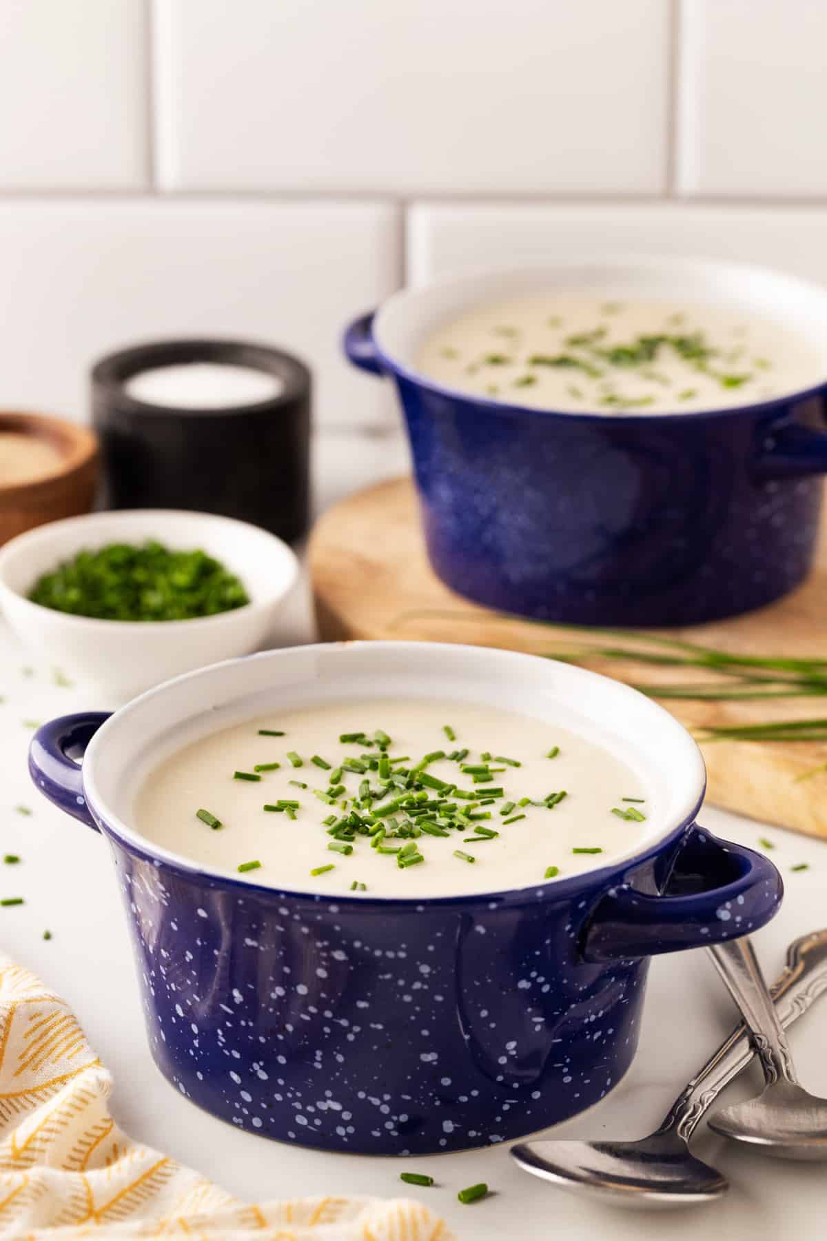 Front view of bowls of vichyssoise with a bowl of chives. 