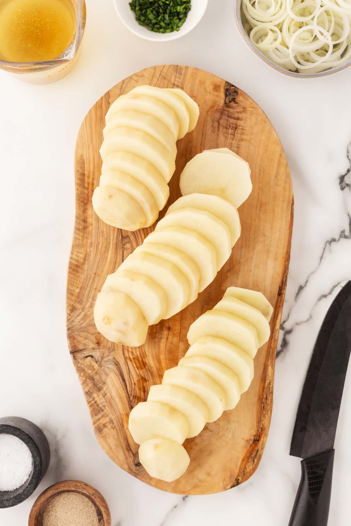 Potatoes sliced on a cutting board. 