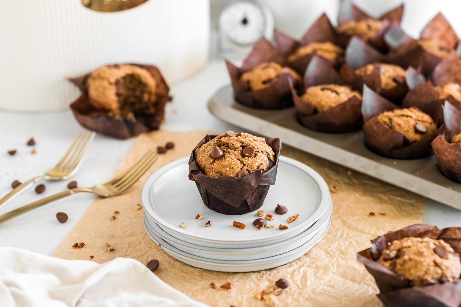 Muffins in a muffin pan plus on a plate and one in the background with a bite taken. 