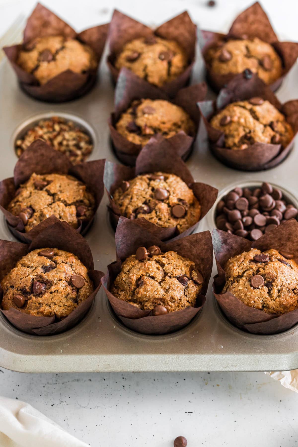 Muffins plus chocolate chips and pecans filling holes of the muffin tin. 