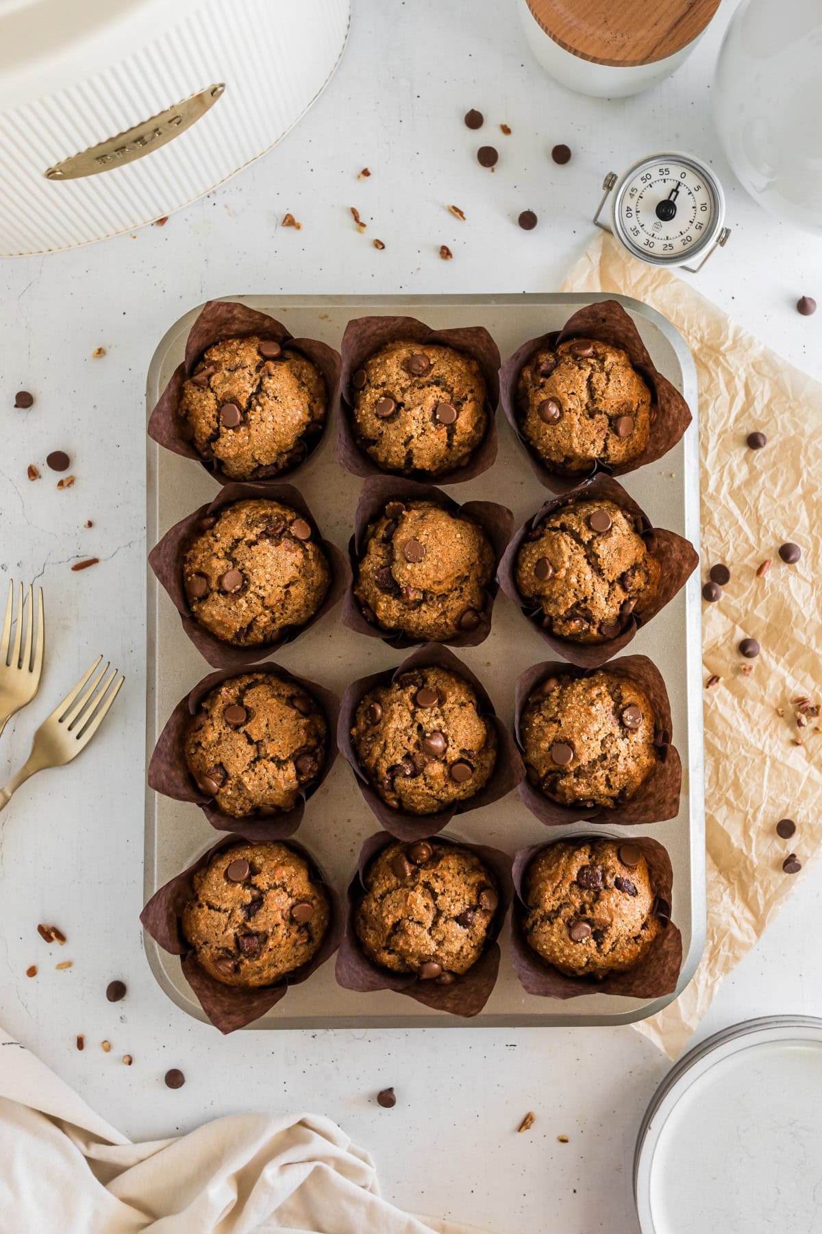 Overhead zoomed out shot of Banana Nut Muffins with chocolate chips in the muffins and scattered around. 