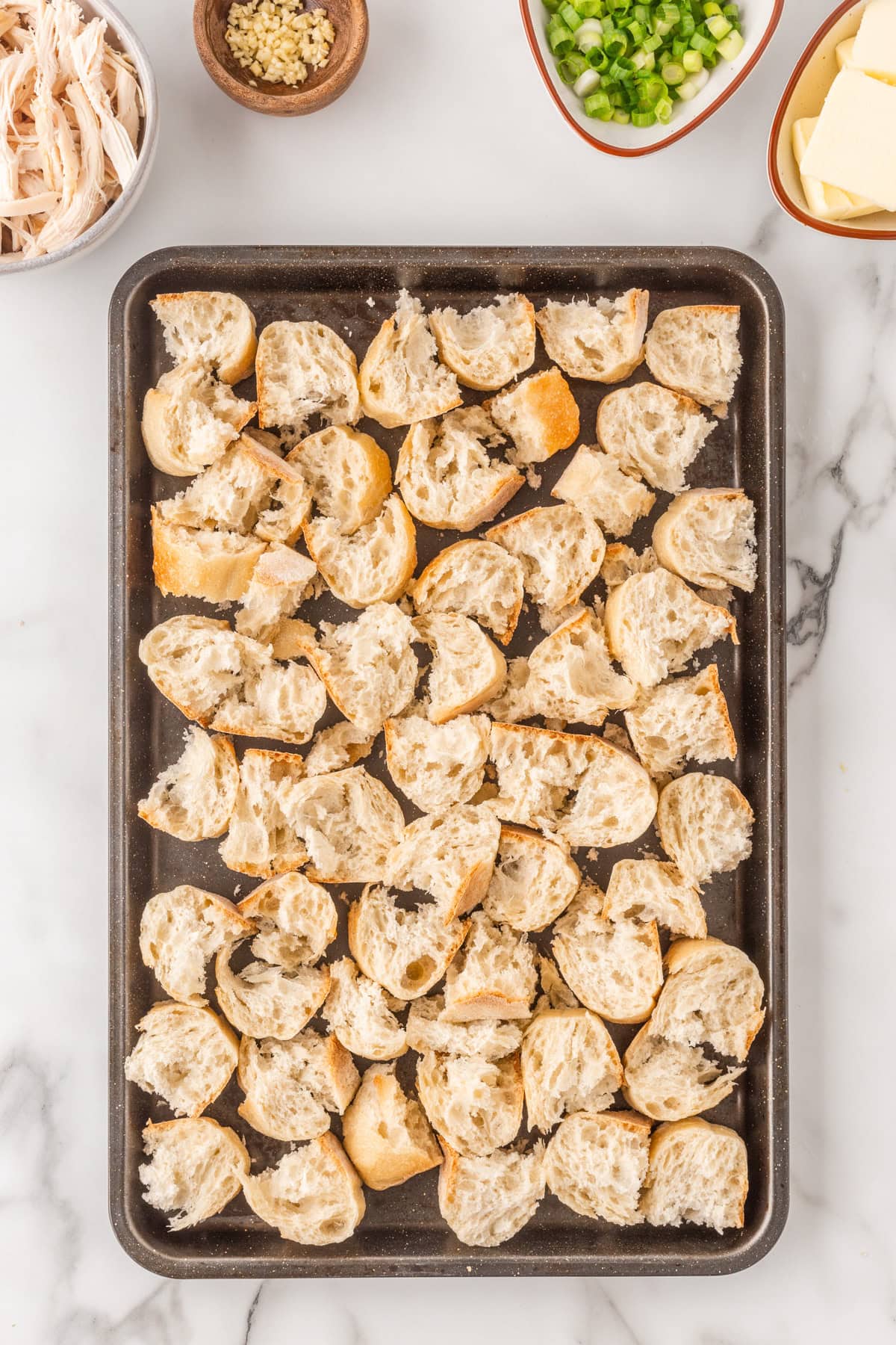 Large chunks of baguette on a baking sheet. 