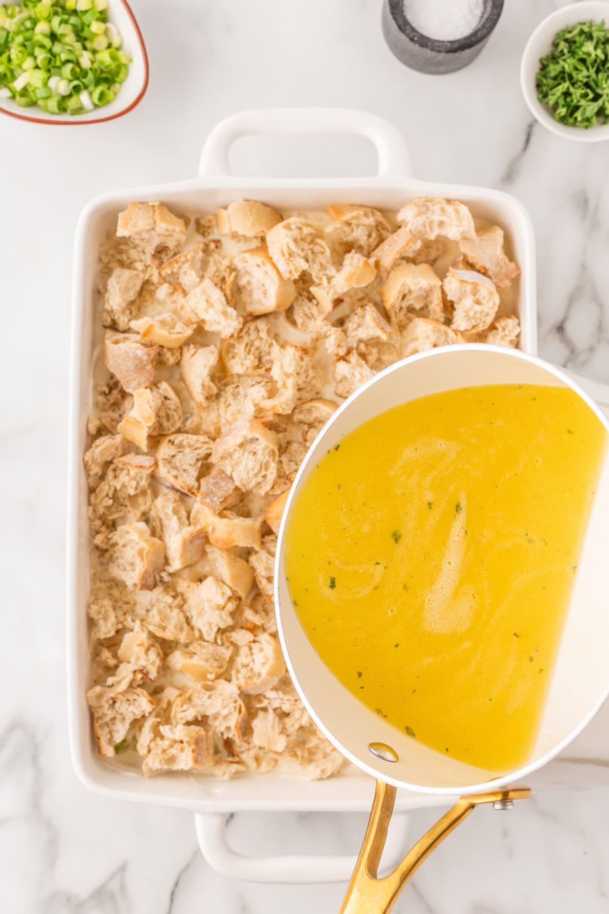 Pouring the chicken broth onto the bread. 