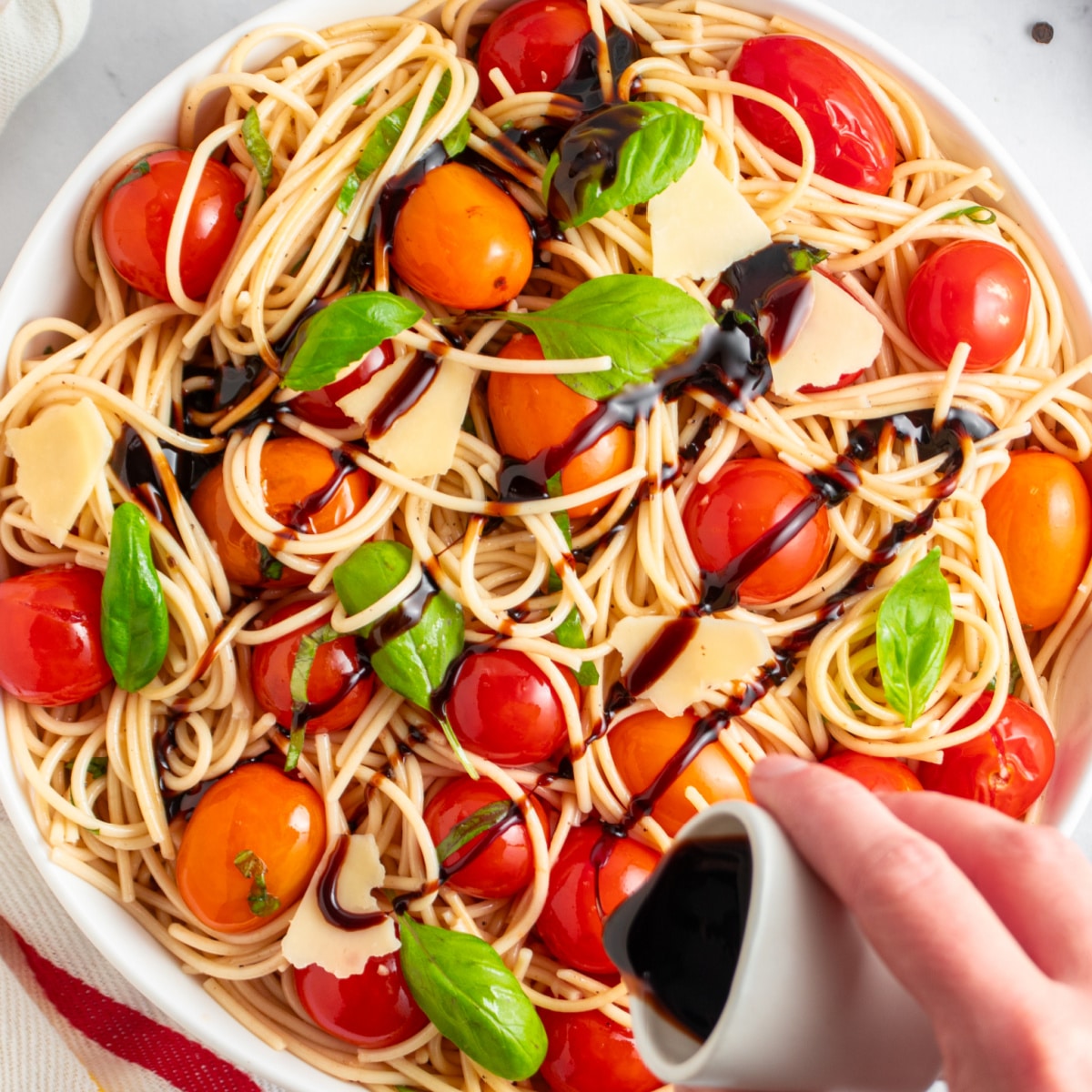 Drizzling balsamic vinegar on fresh tomato pasta. 