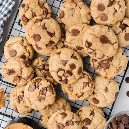 Peanut Butter Chocolate Chip Cookies piled on each other on cooling racks..